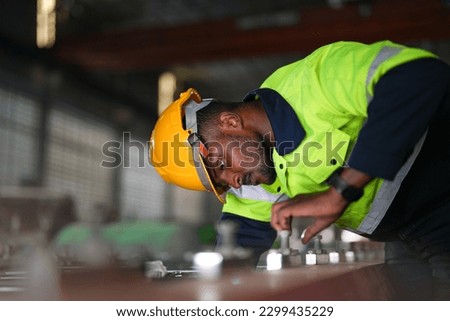 Factory engineer African man checking and reparing mahine at heavy factory.Worker works at heavy machine at industry factory. with machinery equipment plant technology. Royalty-Free Stock Photo #2299435229