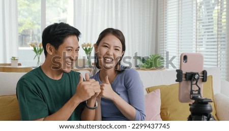 Young adult cute asia couple fun play dancing music game on  reel   app at home selfie camera record video stories Man woman r joy showing vlog trendy talent sit relax at sofa Royalty-Free Stock Photo #2299437745