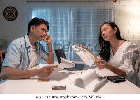 Stressed Asian couple fighting over unpaid debts. Royalty-Free Stock Photo #2299453141