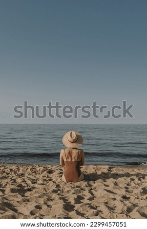 Pretty woman sitting on beach sand and watching at sea and sky. Minimal summer vacation concept. Chilling, relaxing near ocean inspirational composition