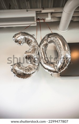 Silver balloons marking 30 year birthday in an office.