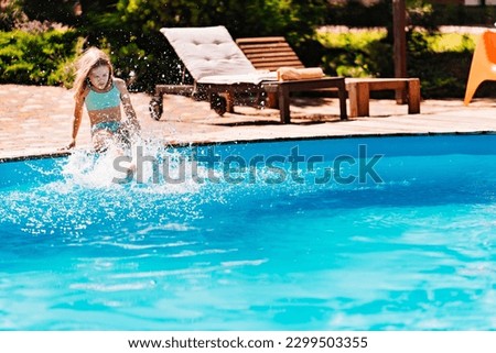 Cute and funny blonde teenage girl in a swimsuit sits on the side of the pool. Safe rest with children by the water. travel and tourism. happy and carefree childhood 