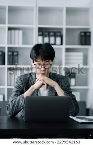 Portrait of a young man thinking sitting at his desk in the office. Royalty-Free Stock Photo #2299542163