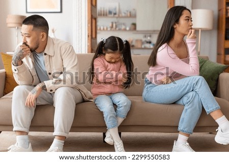 Family Struggles. Upset Japanese Parents And Daughter Sitting With Sadly Bowed Heads Depressed After Intense Conflict, Having Tense Moment Posing On Couch At Home. Conflicts And Unhappiness Problem Royalty-Free Stock Photo #2299550583