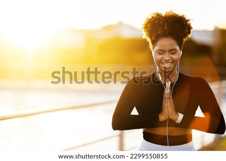 Sunrise Meditation. Portrait Of Young Black Woman Practicing Yoga Outdoors, Beautiful Sporty African American Female Meditating With Eyes Closed And Listening Music In Earphones, Copy Space Royalty-Free Stock Photo #2299550855