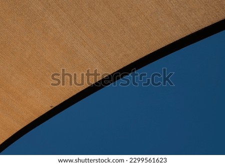 Looking up, corner of a patio umbrella against a blue sky                               
