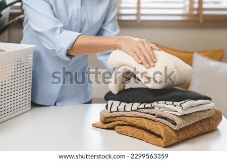 Feel softness, asian young woman, female hand holding pile clothing from table, stack folding clean clothes after washing, laundry and dry. Household working at home. Laundry and maid concept. Royalty-Free Stock Photo #2299563359