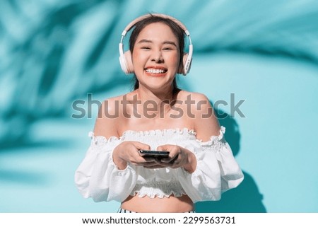delight freshness asia woman hand using smartphone application device choosing song for headphone listen,summer vacation woman smiling enjoy day time of summer travel studio shot on colour background Royalty-Free Stock Photo #2299563731