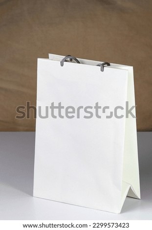 White paper shopping bag, present bag standing on white table with shallow focus.