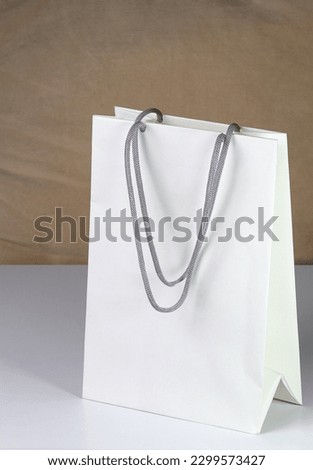 White paper shopping bag, present bag standing on white table with shallow focus.