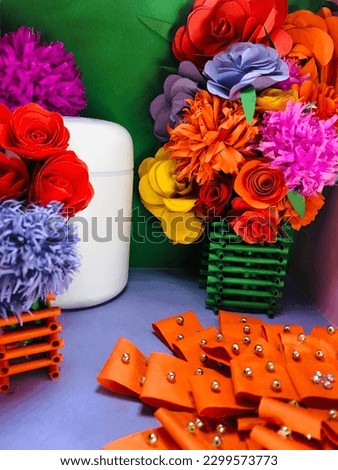 A beautiful paper flowers in this picture. This flowers in the box. The inside of the box has different kind of flowers amd different kind of colours. It has two paper flower vase. Beautiful image.