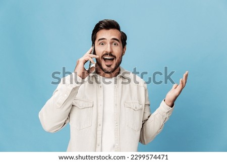 Portrait of a brunette man talking on the phone close-up mobile and internet online, animation open mouth, on a blue background in a white T-shirt, copy space 