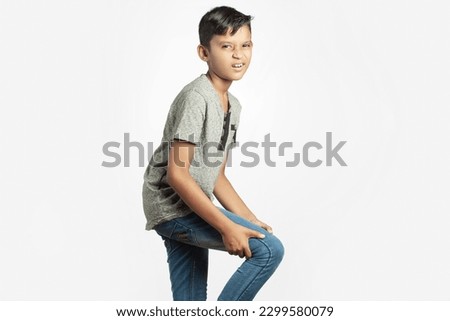 indian cute boy holding his broken thigh leg in white background Royalty-Free Stock Photo #2299580079