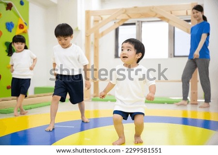 Cute children enjoy dancing and gymnastics in an indoor educational facility. A boy, a girl and a teacher.