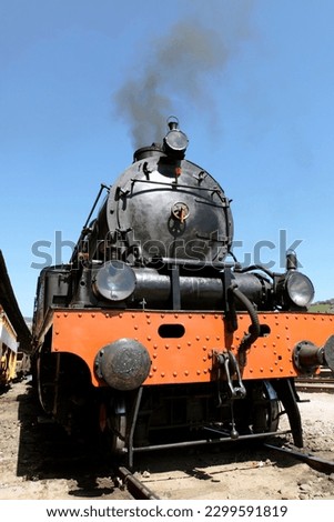 Detail of Vintage steam engine, working, with smoke, against blue sky