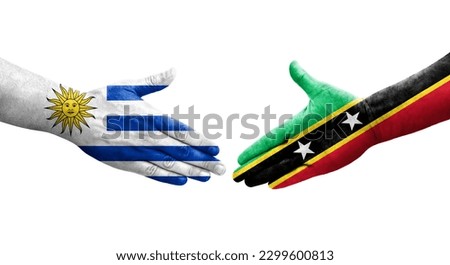 Handshake between Saint Kitts and Nevis and Uruguay flags painted on hands, isolated transparent image.