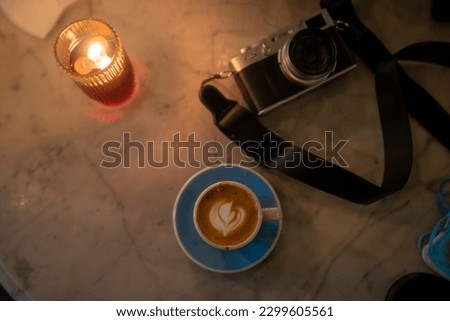 a top shot of Piccolo latte coffee with latte art on cafe table with retro camera and candle in the background.