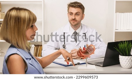 Young woman on a consultation with a male surgeon or therapist in his office. anatomical stomach model on work desk of doctor Royalty-Free Stock Photo #2299609573