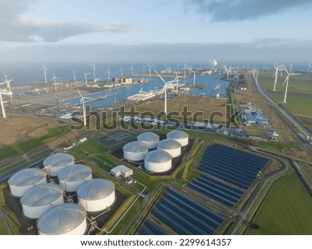 Experience the energy transition in action with an incredible aerial drone video of oil storage silos and solar panels coexisting in the Eemshaven port. Royalty-Free Stock Photo #2299614357