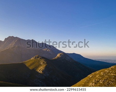Sun rising over Cradock Peak in the Majestic Outeniqua Mountains, With the City George down towards the sea.  George Western Cape, South Africa, May 2023 Royalty-Free Stock Photo #2299615455