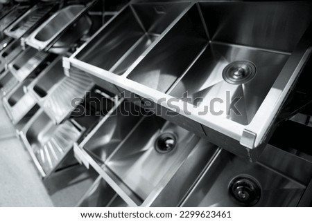 Angle view of rows metal kitchen sink at the showroom of a large store.