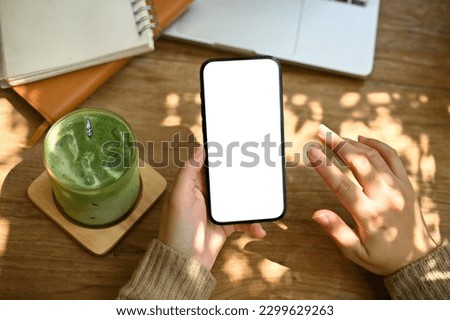 Top view of a woman in comfy sweater using her smartphone while remote working and relaxing at a cafe.