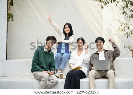 Image of happy and cheerful Asian college students sitting on a bench at a campus relaxation area together. Friendship, togetherness, university lifestyle