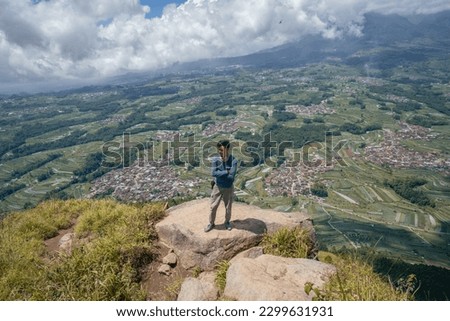 Young man Indonesian hiking mountain through the forest and foot path. The photo is suitable to use for adventure content media, nature poster and forest background.