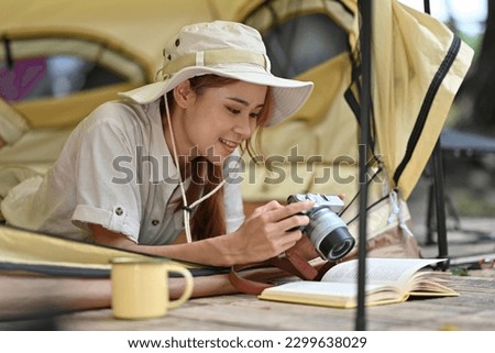 Young female tourist in safari dress Viewing photos on camera while lying inside the tent.