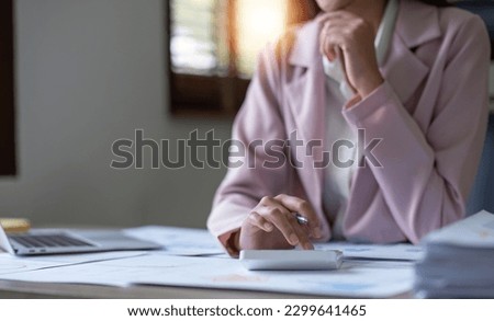 Close-up of businesswoman hands using a calculator to check company finances and earnings and budget. Business woman calculating monthly expenses, managing budget, papers, loan documents, invoices. Royalty-Free Stock Photo #2299641465