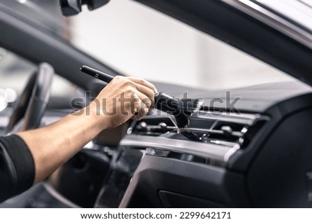 Professional detailing a car in the studio, hands with brush cleaning car interior from a dust, vehicle care concept Royalty-Free Stock Photo #2299642171