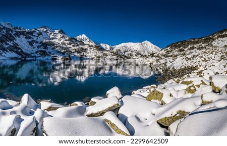 Panorama of the frozen first Bunderishko lake, Ribnoto ezero (Ribno lake) in Pirin mountains, Bulgaria. Winter landscape with Muratov and Vihren peaks. Royalty-Free Stock Photo #2299642509