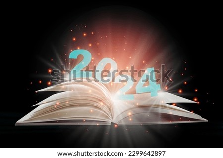 New year 2024 on open white paper fantasy book with shining pages isolated on black background. Miracle happiness holiday concept and mystery beginning idea