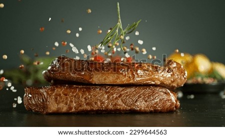 Close-up of falling salt and pepper on tasty beef steaks on table, freeze motion. Royalty-Free Stock Photo #2299644563