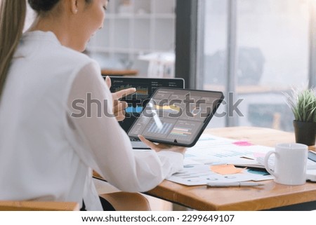 A businesswoman or accountant using tablet to analyze financial investments and business and marketing growth on a data graph. The concepts of accounting, economics, and commercial analysis Royalty-Free Stock Photo #2299649107