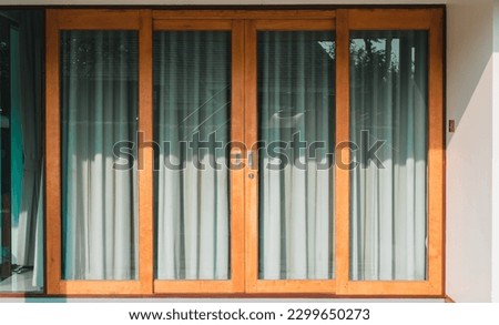 door made of wood and glass. A gray-green curtain is within. Halfway through the glass, the sun is visible. interior of living room