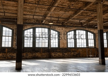 Sunlight Shining through Loft Windows casting Shadows.  One pendant light and one high top table fill the space.  Both the floor and ceiling are aged wood plank. Royalty-Free Stock Photo #2299653603