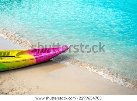 Colorful kayak with nobody on clean sandy beach and blue sea background with copy space, activity equipment prepare for hotel or resort guests on holiday summer vacation travel.