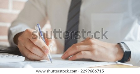 close up senior banker or businessman hand use pen to sign or write on legal paperwork about approval or deal contract at table in office for business lifestyle concept