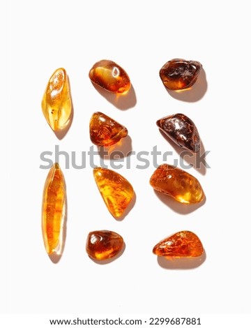 Set of Natural gemstone amber stones with glare shadows, yellow orange colored isolated on white background. Natural mineral Transparent amber gems different forms, flat lay pattern, minimal top view Royalty-Free Stock Photo #2299687881