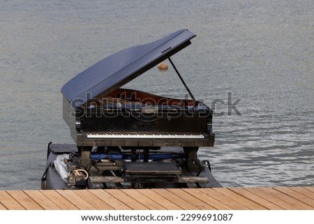 Classic piano floating on the lake jetty with the lid open and a built-in microphone