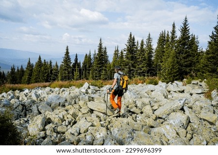 A solo journey through the wilderness in the mountains, a guy walks on stones at a height, a mountain range, hiking equipment, a hike in the forest. High quality photo Royalty-Free Stock Photo #2299696399