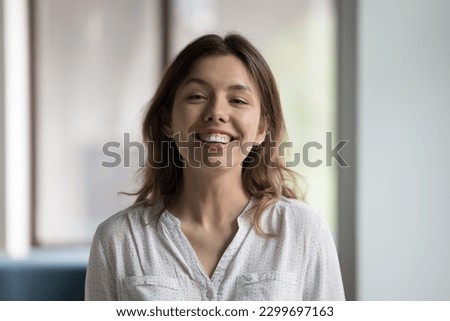 Head shot attractive female employee smile staring at camera, looks confident, posing alone for corporate photo, celebrate promotion, young female student enjoy successful graduation, good exam pass