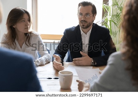 Department brainstorming in office board room, staff led by male CEO discussing new project, sharing ideas thoughts and sales statistics, provide information to shareholders engaged in formal meeting Royalty-Free Stock Photo #2299697171
