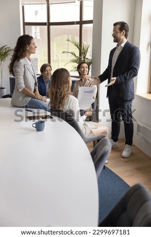 Confident businessman, male boss in suit explains new project details, share business strategy, makes speech stand in front of company staff members during corporate group briefing in conference room Royalty-Free Stock Photo #2299697181