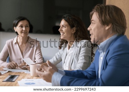 Business people engaged in teamwork in office, focus on pretty Hispanic businesswoman, take part in briefing with mature workmates in conference room prepare project, discuss details feel satisfied Royalty-Free Stock Photo #2299697243