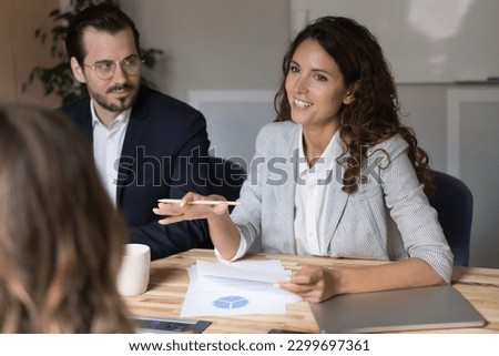 Millennial businesswoman makes formal presentation to colleagues or business partners in modern office, discuss terms of deal or cooperation, consider business plan or project, reviewing sales stats Royalty-Free Stock Photo #2299697361