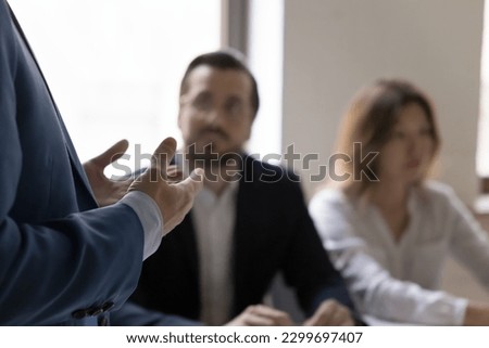 Unknown businessman, project leader in formal suit gesticulates while makes speech or presentation, talk at group meeting, close up cropped view. Communication, negotiations, mentoring, seminar event Royalty-Free Stock Photo #2299697407