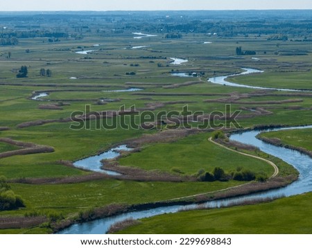 Meandering Narew river near Tykocin in Poland - drone aerial view, landscape photography, green fields, meadows, sunny day