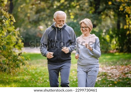 Smiling senior couple jogging in the park. Sports activities for elderly people Royalty-Free Stock Photo #2299730461
